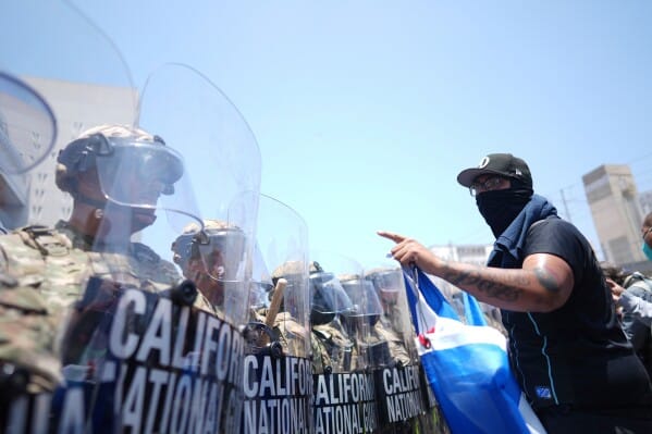 Protesters shout across a line of soldiers.