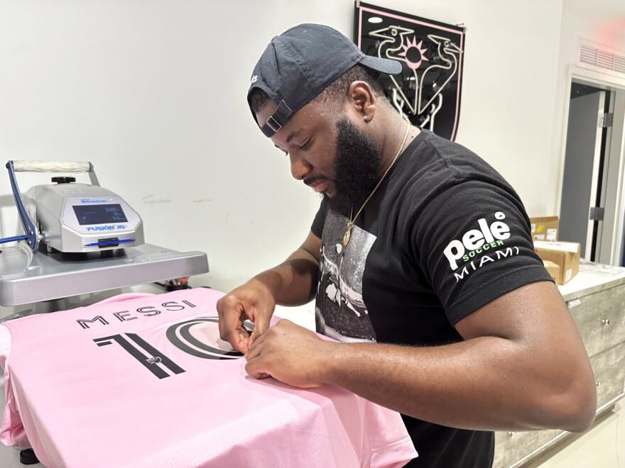 A worker carefully prints “Messi 10” on an Inter Miami jersey at a Pelé Soccer shop in Miami.