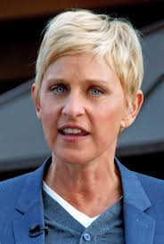 Ellen DeGeneres speaking outdoors, dressed in a blue blazer and white shirt.