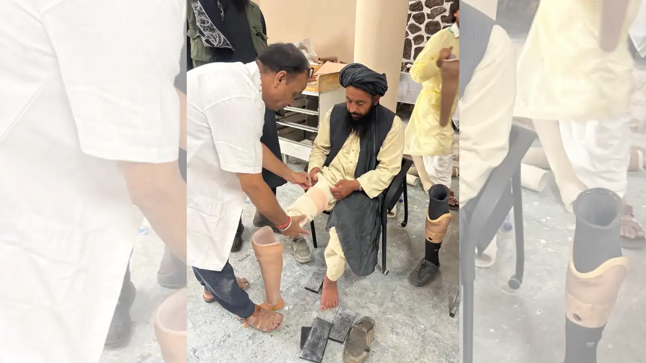 Man being fitted with a Jaipur Foot prosthetic limb by a technician, surrounded by artificial legs and tools.