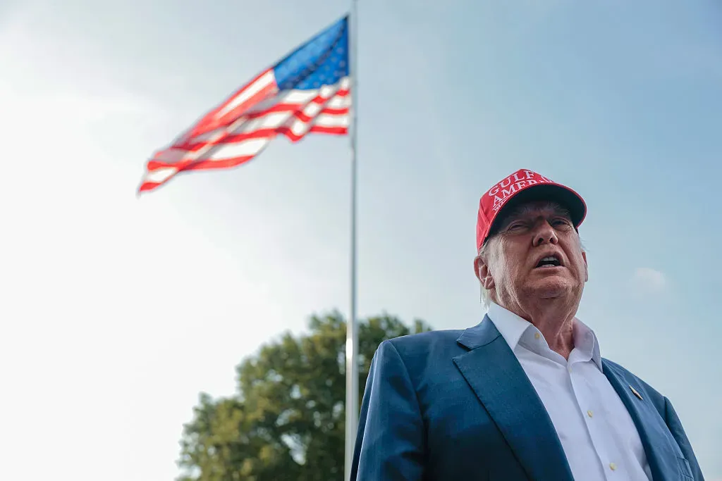 Donald Trump speaking at a campaign rally in Florida, holding a ceasefire document.