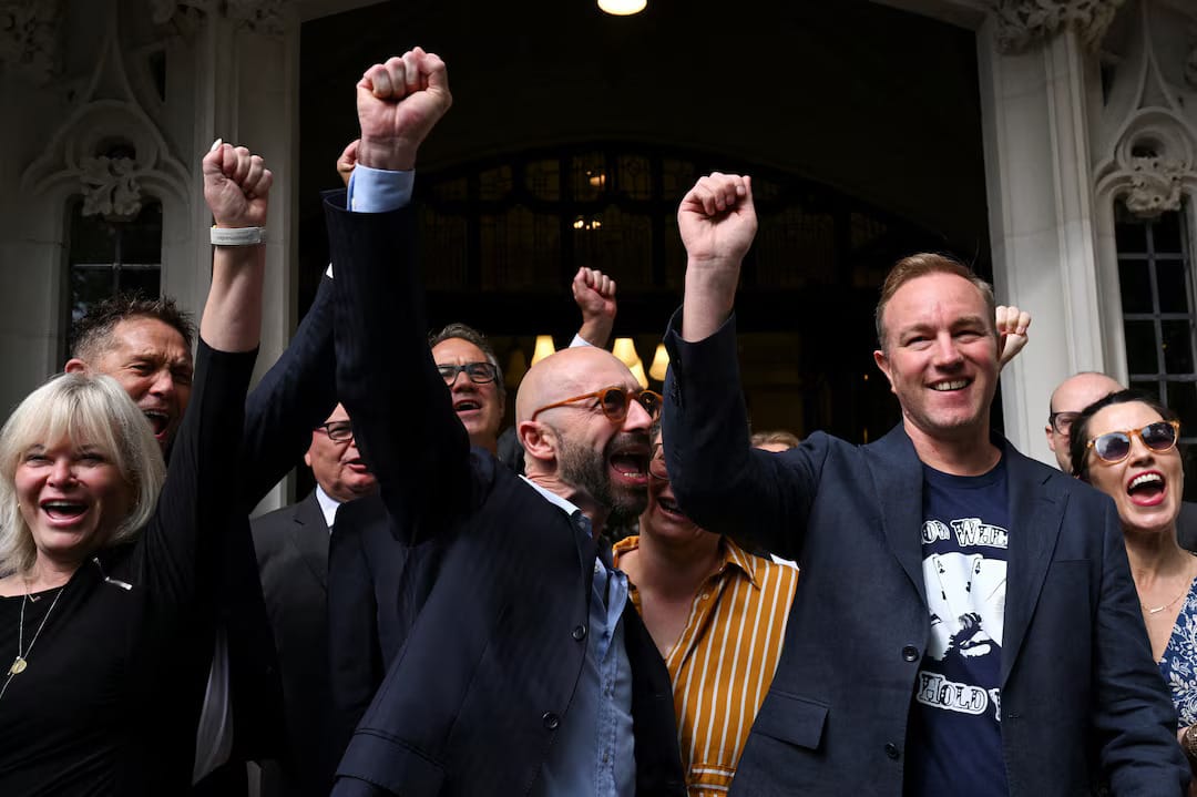 Group photo of Hayes and Palombo with raised fists in front of Supreme Court entrance.