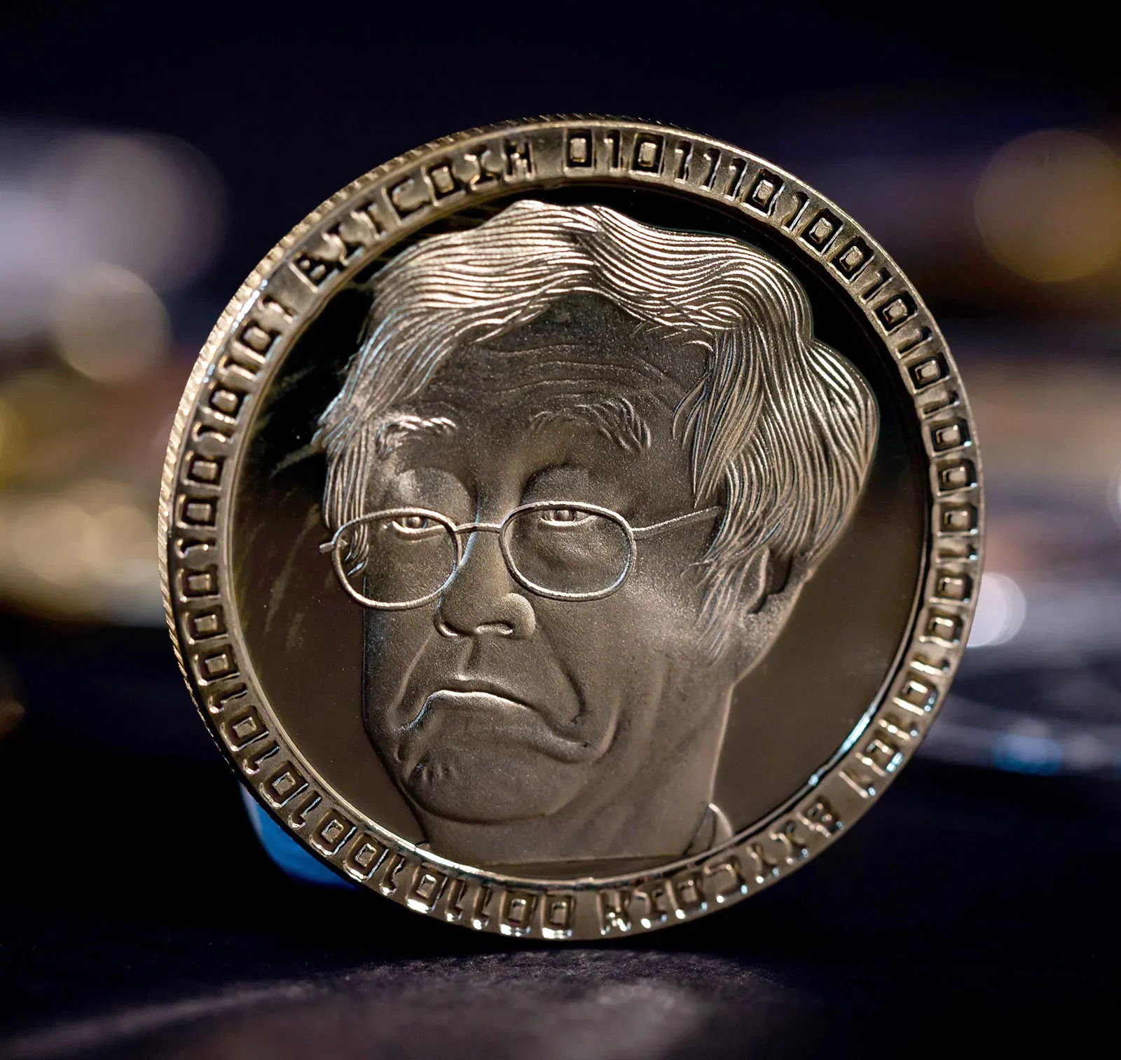 Close-up of a coin engraved with a stylized image representing Satoshi Nakamoto.