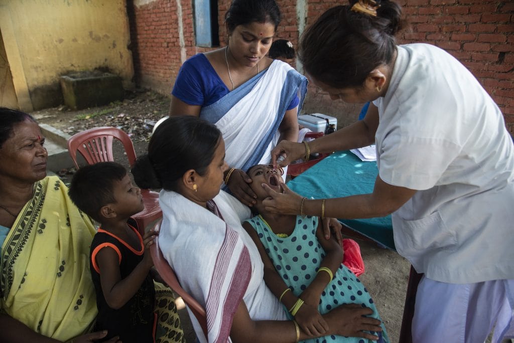 A nurse in traditional sari gives a vaccine to a toddler.