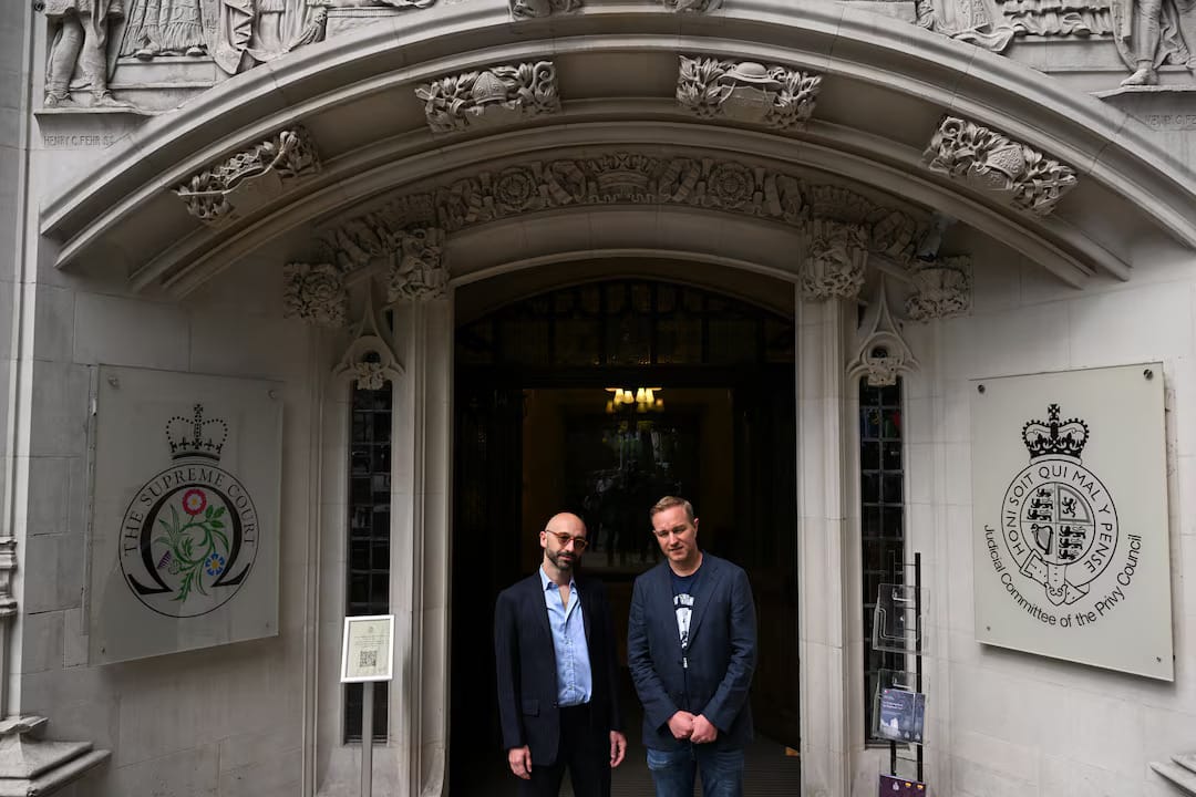 Two men—Tom Hayes and Carlo Palombo—standing in front of the ornate Supreme Court doorway, dressed in smart casual.
