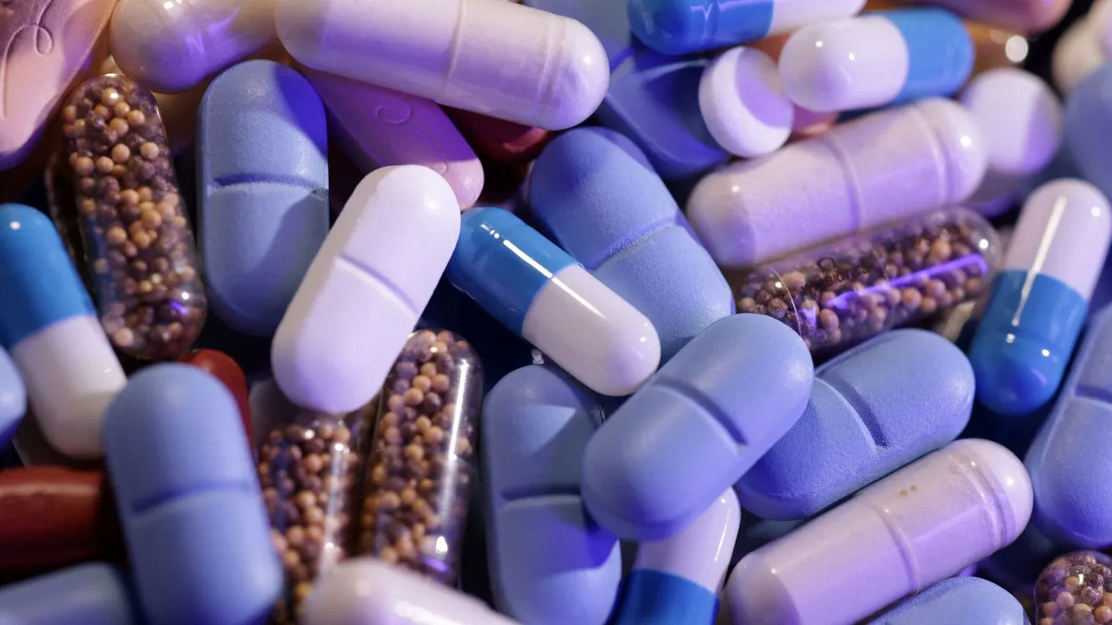 A close-up image of assorted colorful capsules and pills, highlighting the pharmaceutical industry's global scale and complexity.