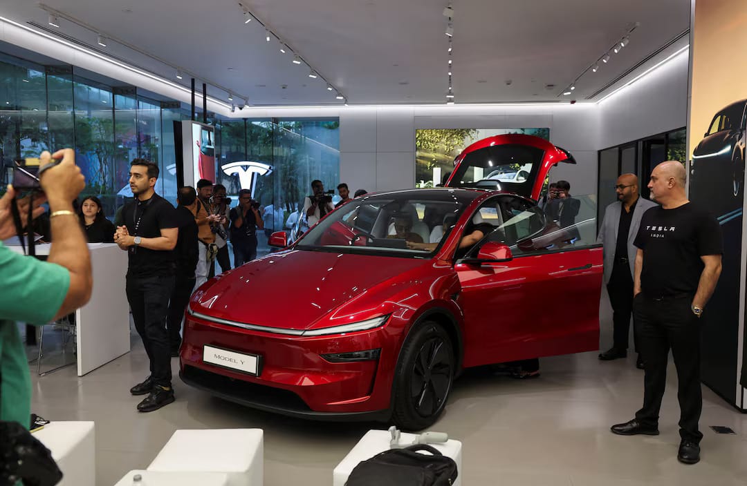 Media personnel photographing a Tesla Model Y inside the showroom.