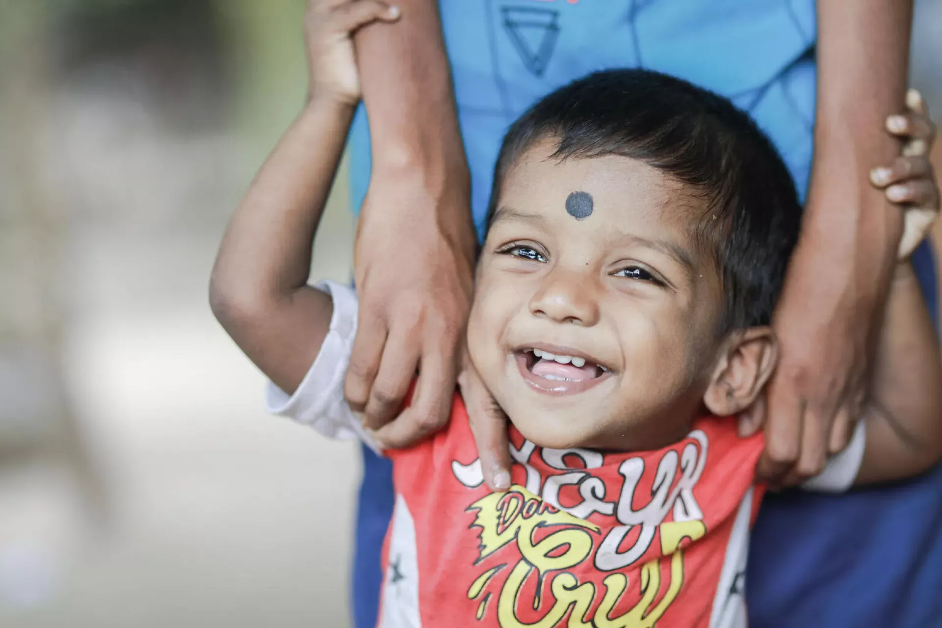 A toddler grins as a healthcare worker holds them, vaccine freshly administered.