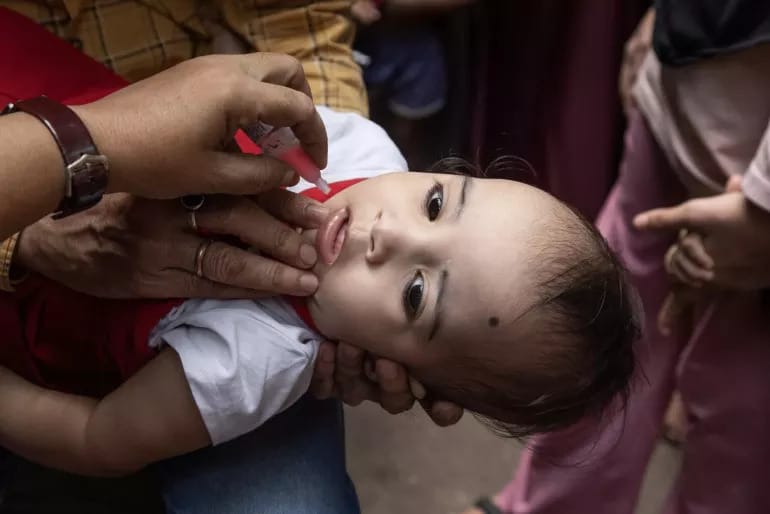 A child is getting a dose of medicine by a healthcare worker, at a heath centre