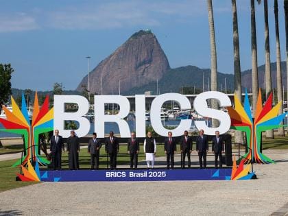 BRICS leaders standing in front of a large BRICS 2025 sign with Sugarloaf Mountain in the background.