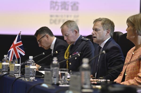 British and allied defence officials sit at a conference table with microphones