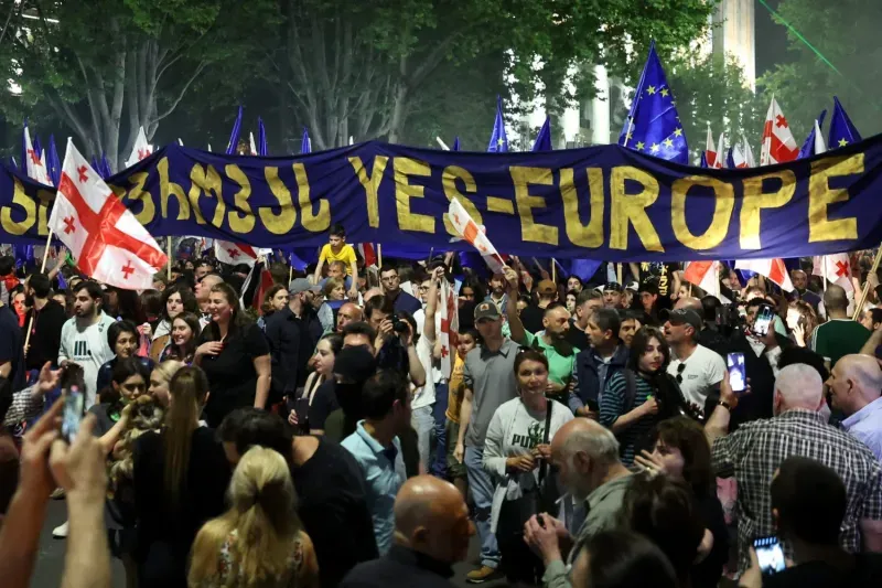 A large crowd of Georgian protesters holds a giant "YES EUROPE" banner during a pro-democracy rally in Tbilisi.