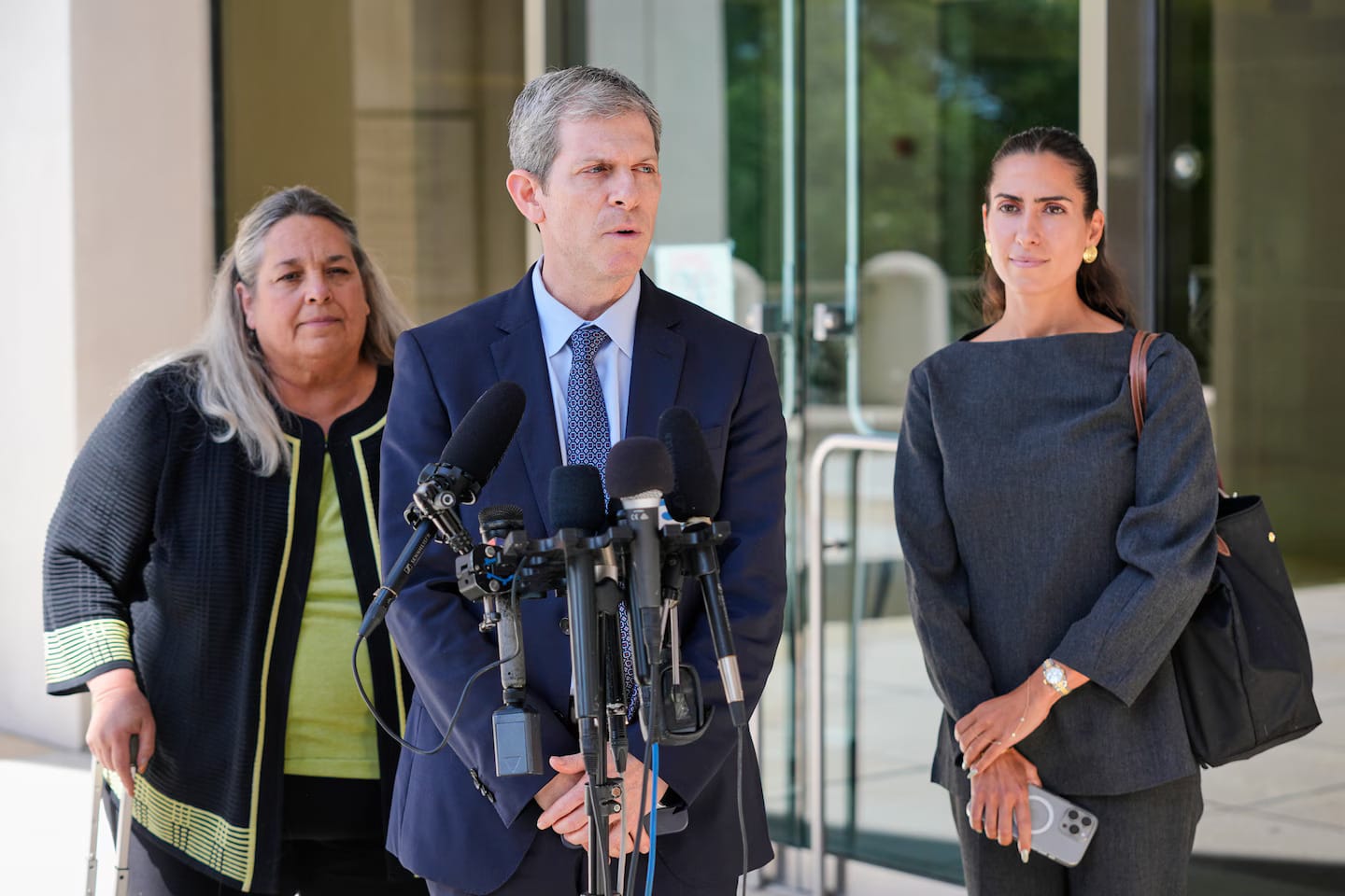 Ghislaine Maxwell's legal team speaking at a press conference, with microphones set up outside a courthouse.