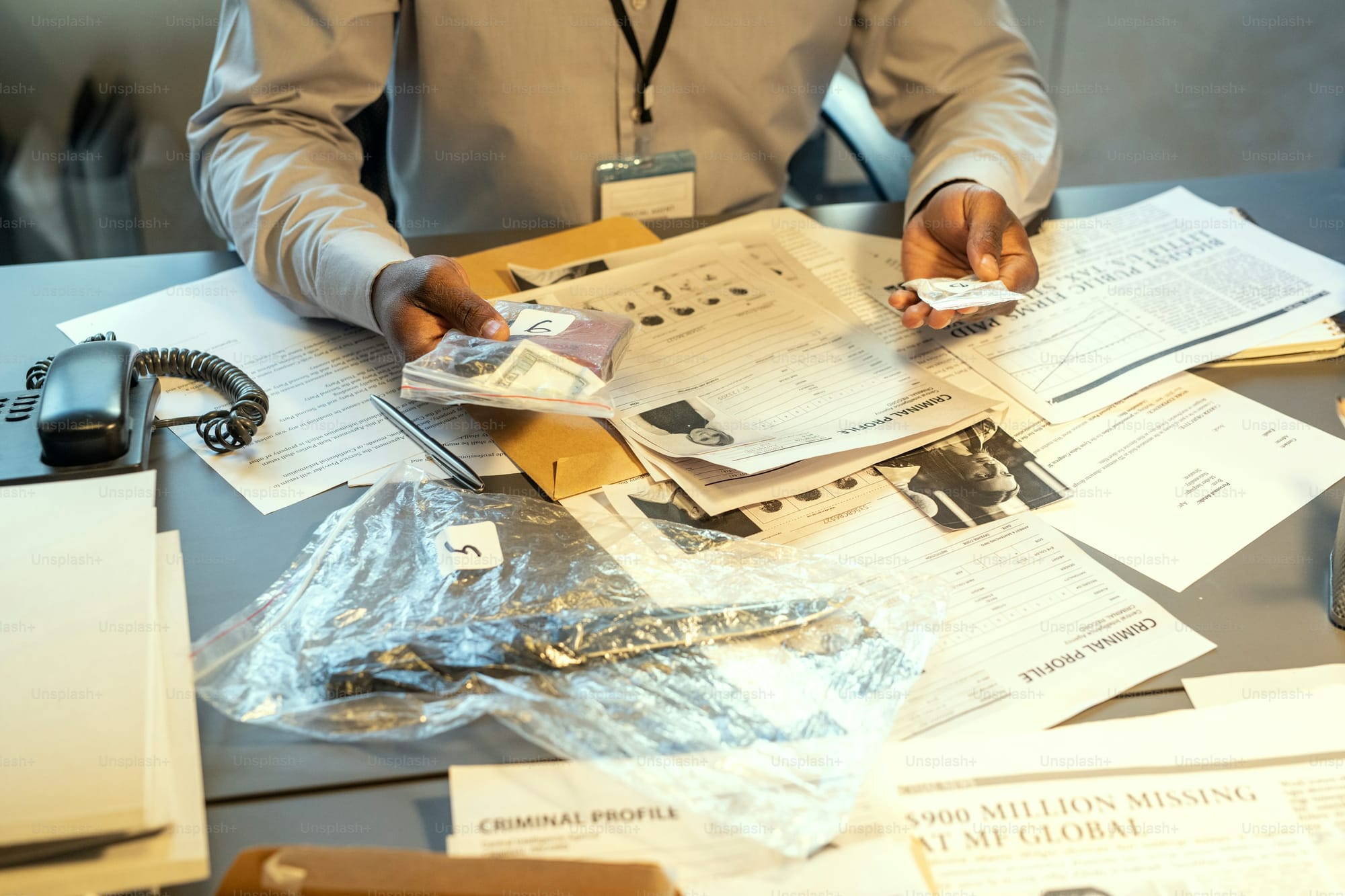 Forensic analyst organizing documents and evidence on a cluttered workspace