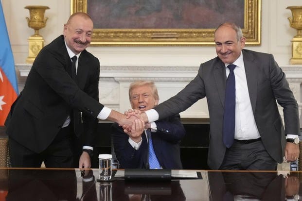 Azerbaijani President Ilham Aliyev, former U.S. President Donald Trump, and Armenian Prime Minister Nikol Pashinyan clasp hands together