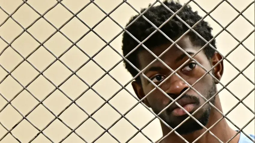 A powerful image showing Lil Nas X through a mesh or jail setting.