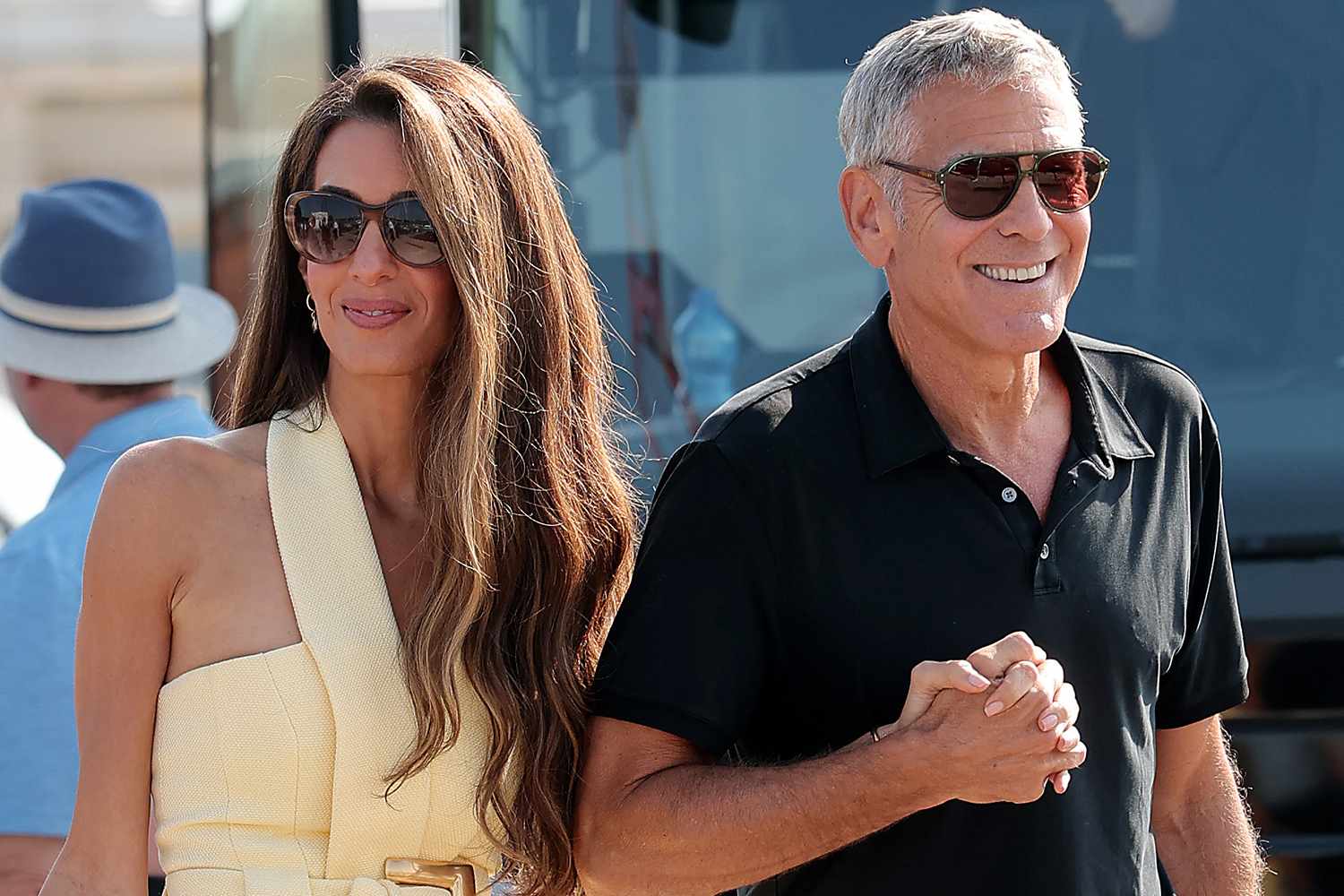 A sharply framed shot capturing George’s relaxed, Riviera-inspired look: sunglasses, a chic polo, and neutral tones