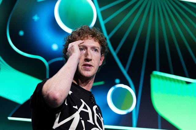 Mark Zuckerberg speaking on stage with a futuristic, tech-themed background at a Meta AI event.