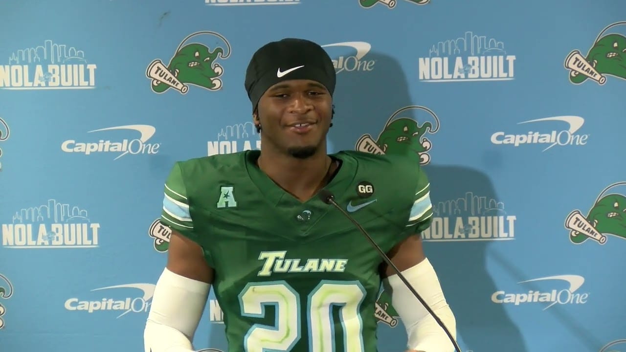 Tulane Green Wave football player wearing number 20 jersey speaks at a press conference with NOLA Built and Capital One logos in the background.