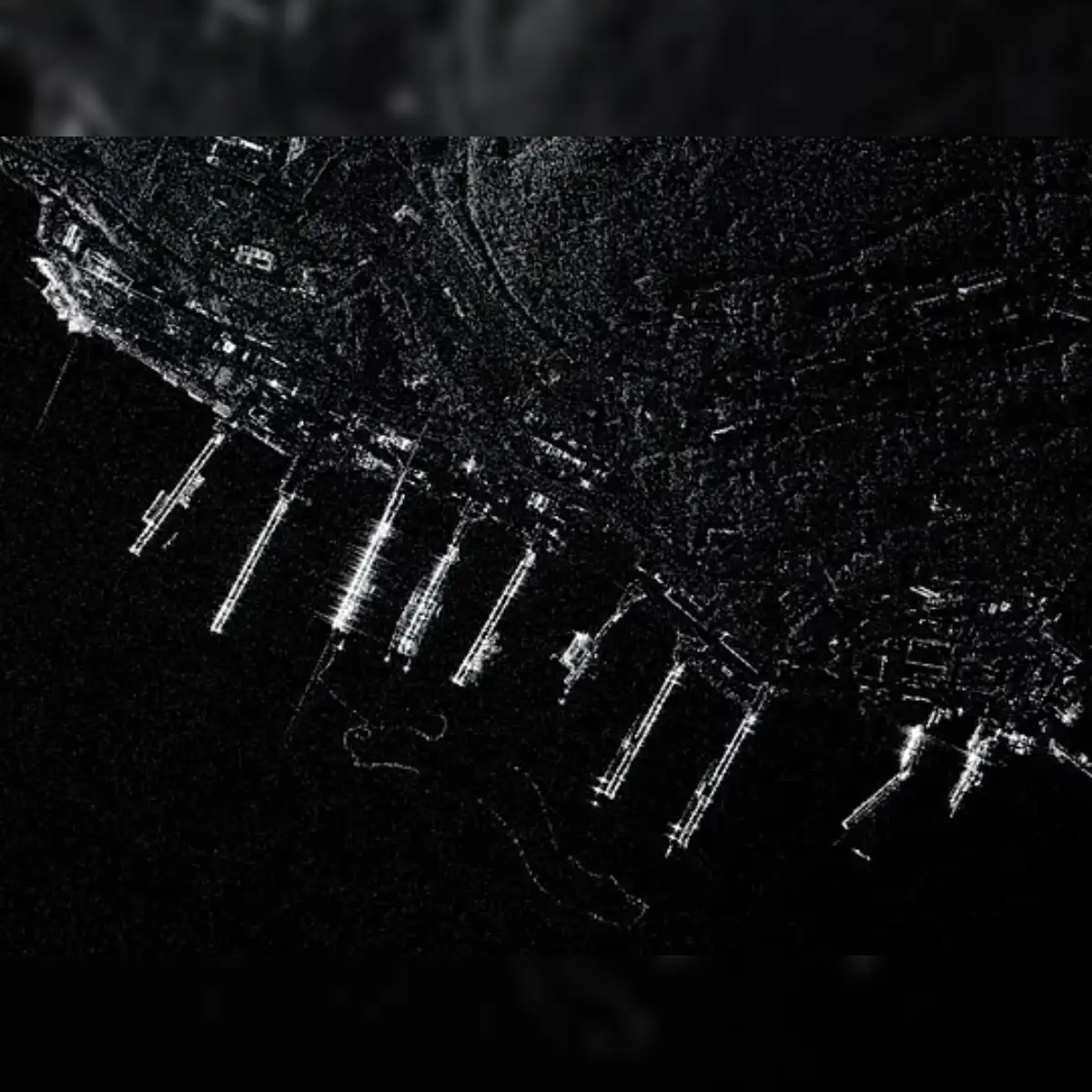 Synthetic Aperture Radar (SAR) image of the Petropavlovsk-Kamchatsky submarine base at night or under cloud cover, showing illuminated piers and vessel outlines.