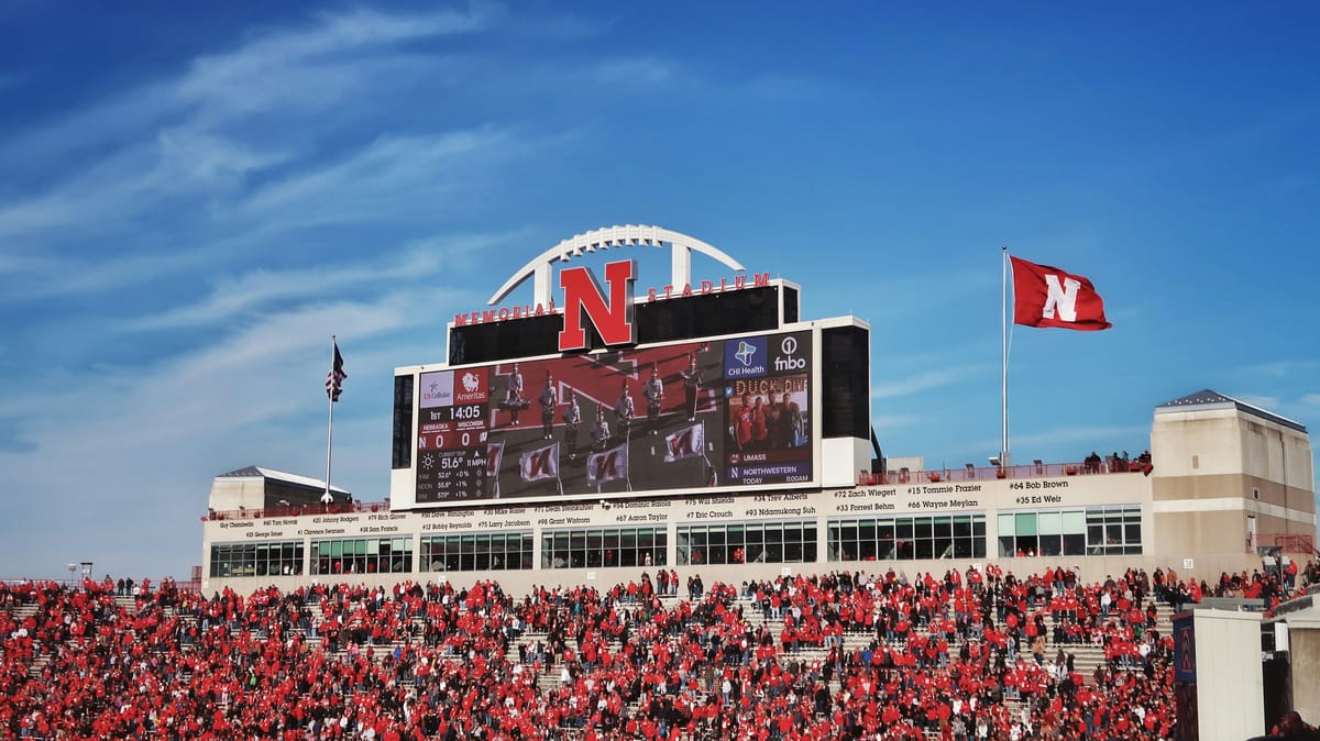 A clear view of a stadium scoreboard surrounded by fans during daylight.