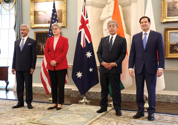The full delegation standing in front of national flags