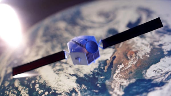 A close-up render of a small Earth observation satellite in orbit, with solar panels extended, flying over a blurred view of Earth’s surface and clouds.