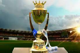 Golden Asia Cup trophy displayed on a podium inside a cricket stadium, with dramatic clouds and sunlight in the background.