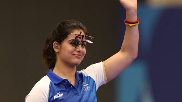 Indian shooter with rifle in hand during a competition, focused and ready to take a shot in front of the target background.